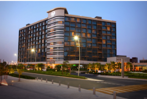 Evening view of Yas Island Rotana with illuminated surroundings and a road in front.