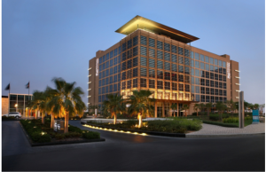 A dimly lit evening view of Centro Yas Island featuring the hotel front with palm trees 