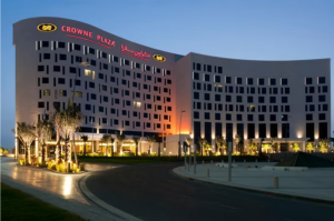 Night view of Crowne Plaza Abu Dhabi featuring its well-lit modern architecture surrounded by landscaped greenery. 