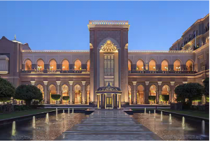 Front view of Emirates Palace featuring its grand entrance and a reflecting pool surrounded by lush greenery.