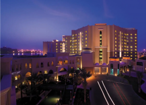 Front view of Traders Hotel, showcasing its expansive, illuminated structure at night.