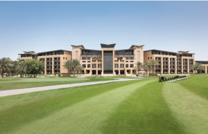 Daytime view of VOGO Abu Dhabi featuring a lush green golf course under a clear blue sky. 