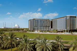 Front view of Park Rotana, showcasing its modern architectural design surrounded by a lush green lawn under daylight. 