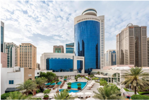 Majestic view of the Royal Meridien Abu Dhabi, featuring a poolside area surrounded by lush palm trees.