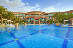 A stunning pool front of Al Raha Beach Hotel with a magnificent hotel structure in the background. 